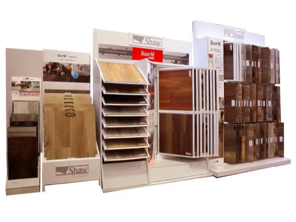 Multiple floor sample displays featuring a variety of wood and laminate designs in natural tones arranged on white branded stands for home improvement.