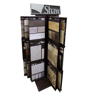 Rotating floor tile sample display stand featuring various natural stone and ceramic tile patterns with a Shaw brand sign on top.