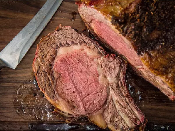 Close-up of a juicy roast beef slice with a browned crust and pink interior resting on a wooden surface next to a carving knife.