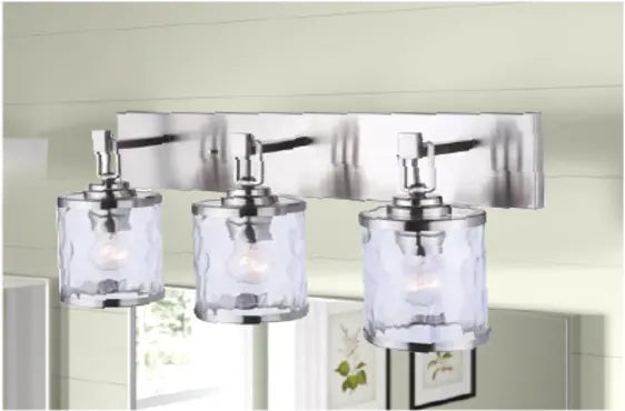 Three-light vanity fixture with textured clear glass shades and brushed metal finish mounted above a bathroom mirror.
